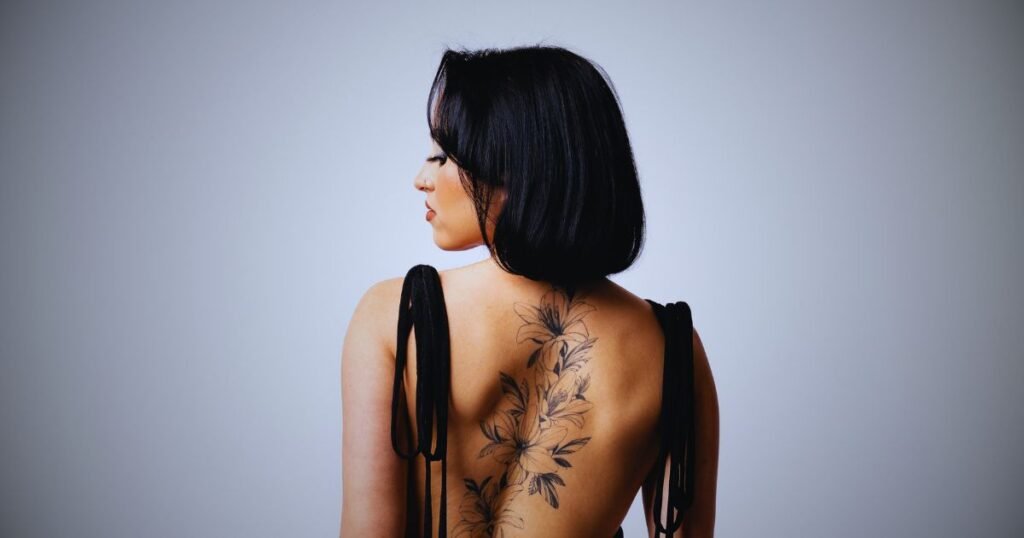 Woman with tattoos and a knife in her back symbolizing betrayal from loved ones and broken trust