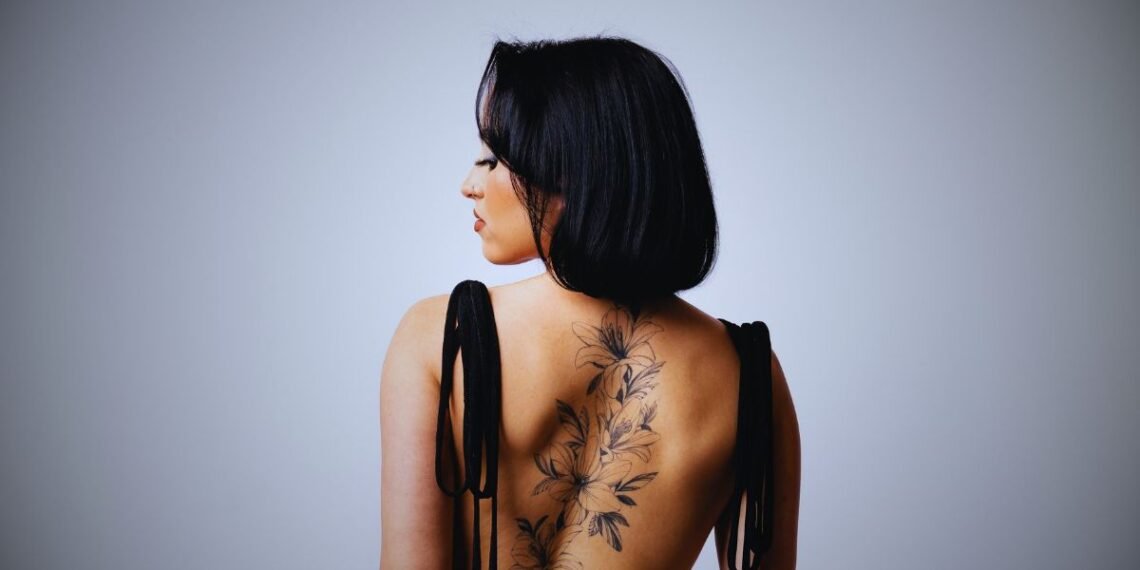 Woman with tattoos and a knife in her back symbolizing betrayal from loved ones and broken trust