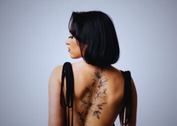 Woman with tattoos and a knife in her back symbolizing betrayal from loved ones and broken trust