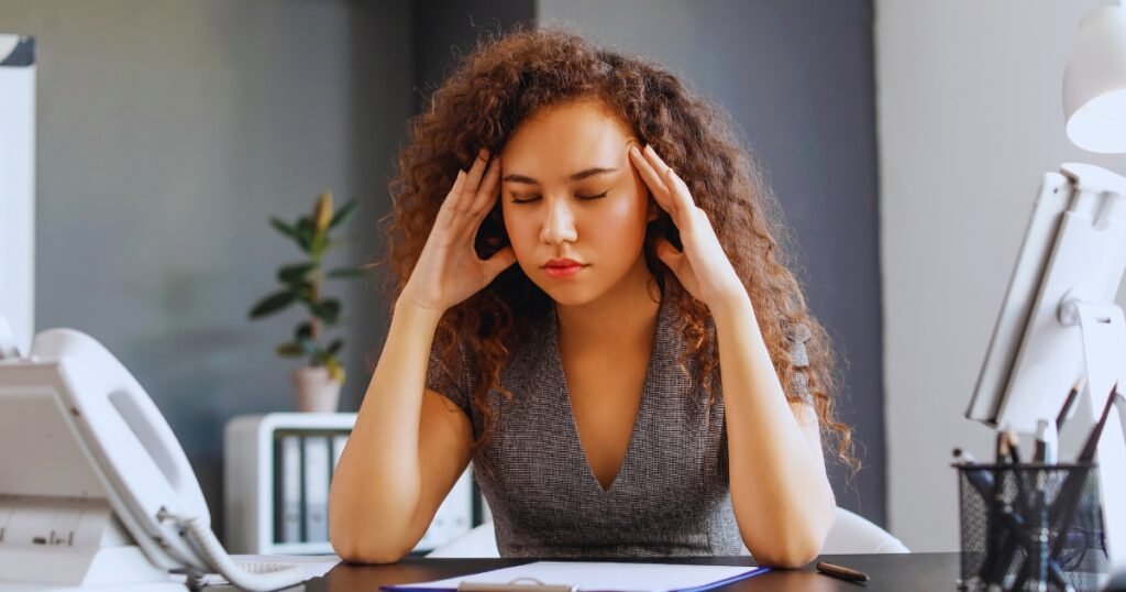 Woman who feels exhausted but can't stop working at her desk