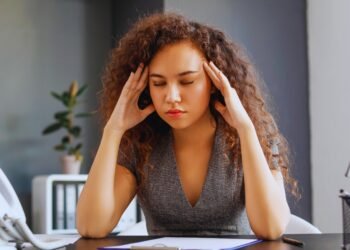 Woman who feels exhausted but can't stop working at her desk