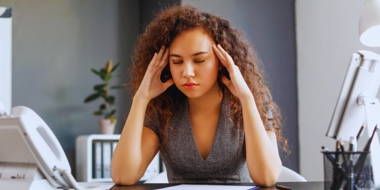 Woman who feels exhausted but can't stop working at her desk